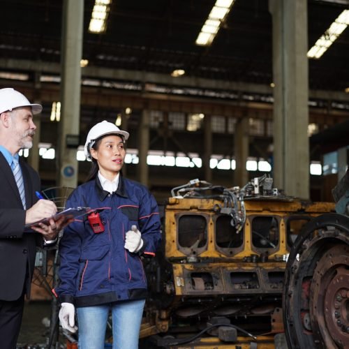 Factory manager or businessman and female engineer in factory. elegant man inspecting factory in industry plant background.