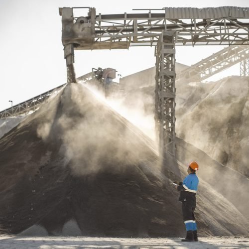 Quarry worker standing beside pile of aggregate in quarry
